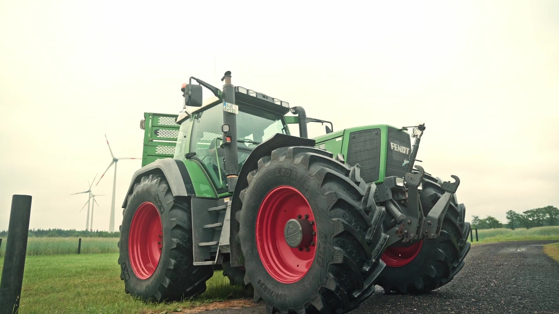 Fendt-Schlepper auf dem Hof, im Hintergrund Windräder